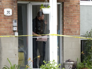 An Ottawa police officer looks out from inside a home at the scene of an overnight homicide in Lowertown in Ottawa on Sunday, July 10, 2016.