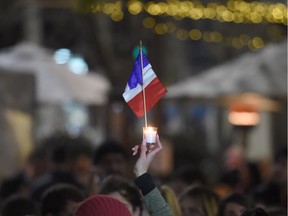 A member of the French community holds up a candle and a national flag during a vigil in Sydney on July 15, 2016.