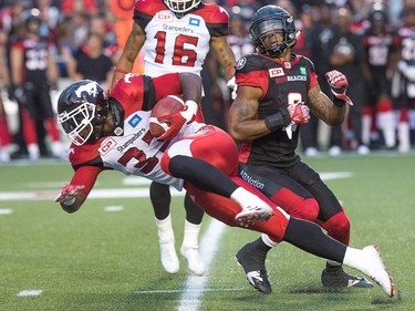 Calgary player Jerome Messam carries the ball past Redblacks player Jermaine Robinson in the second quarter.