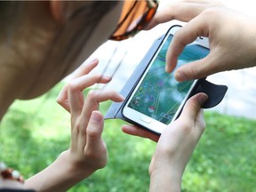 Cathy Chiu (L), John (R) and many gamers showed up at Confederation Park in Ottawa to play Pokemon Go, July 12, 2016. Photo by Jean Levac