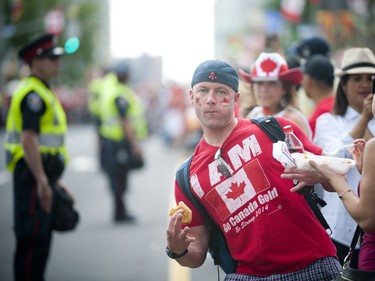 Chad Ireland jumps out between the crowd and police lining Wellington Street during Canada Day festivities in downtown Ottawa, Friday, July 1, 2016.