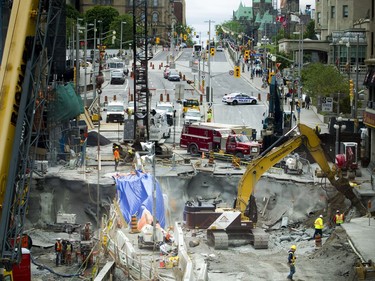 Day 5: Construction crews were at work Sunday June 12, 2016 as pedestrians and shoppers got a peek of the status of the sinkhole from the pedestrian bridge.