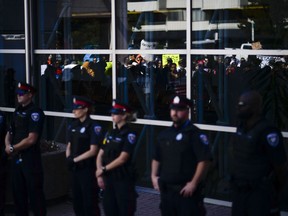 Demonstrators are reflected on the windows of the Ottawa police headquarters as they shout and chant for justice at Ottawa police headquarters during the March for Justice - In Memory of Abdirahman Abdi, on Saturday, July 30, 2016.