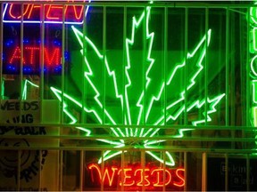 A neon weeds sign illuminates the store front of a medical marijuana dispensary  in Vancouver.