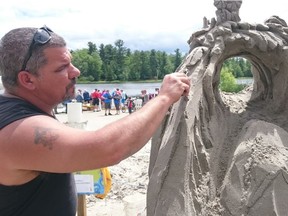 Jean-Francois Gauthier adds some detail to his sand sculpture titled "The Rabbit Hole."