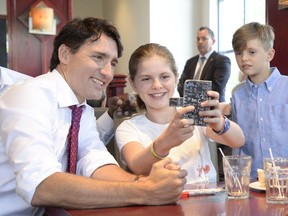 Prime Minister Justin Trudeau takes a photo with Charlotte Farther as her brother James looks on in Aylmer on Wednesday.