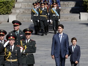 Canadian Prime Minister Justin Trudeau and his son, Xavier, walk to lay flowers at a monument to honor World War II victims in Kiev, Ukraine, Monday, July 11, 2016.