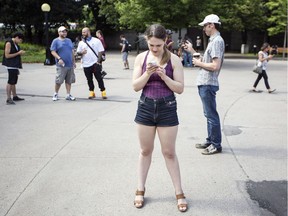 Leanne Sharzer, centre, was one of a couple hundred people who gathered during a Pokemon Go Lure Party in Confederation Park Tuesday July 19, 2016