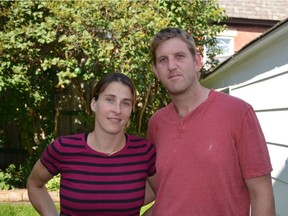 Lindsay Holmes and Michael Holmes stand in their backyard. Behind them is the fence they jumped to save their neighbour being mauled by a pit bull.
