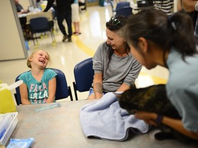 Makayla Gyurcsak, 7, laughs with her mother Irene after hearing from Dr. Michelle Lem, right, that her cat, Gizzie, is fine after receiving a microchip injection.