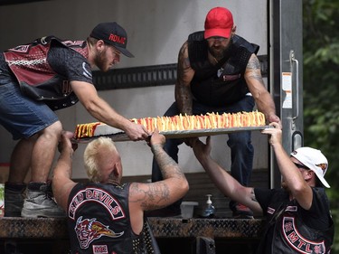 Members of the Red Devils lift a cake with flame detailing into a refrigerated truck outside the Hells Angels Nomads compound during the group's Canada Run event in Carlsbad Springs, Ont., near Ottawa, on Saturday, July 23, 2016.