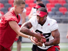 Nic Grigsby carries the ball after taking a hand off from QB Trevor Harris (L) as the Ottawa Redblacks run a walk through practice in advance of their CFL game against the Calgary Stampeders on Friday night.