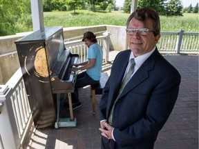 Nik Pope poses with one of his 'Pianos in the Park' at Walter Baker Park in Kanata, which is being played by musician Tyler Kealey.