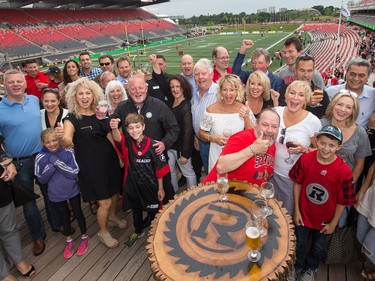 OSEG partner Jeff Hunt (behind the boy putting up his hand on left) gathers with some of his guests he's hosting for a CHEO fundraiser on the patio of his condo unit that looks out onto the field at TD Place.