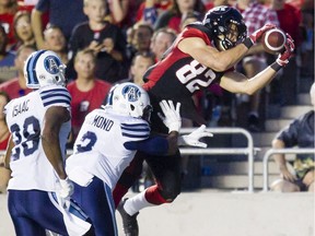 The Ottawa Redblacks' Greg Ellingson makes a diving catch while defended by the Toronto Argonauts' Keon Raymond (2) and Brandon Isaac (28) during the first half at TD Place stadium on Sunday, July 31, 2016.