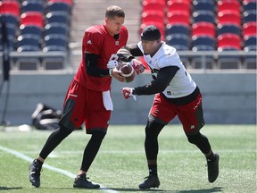Ottawa Redblacks Trevor Harris hands the ball to Nic Grigsby during practice at TD Place in Ottawa Monday July 11, 2016.