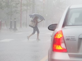 Pedestrians along Somerset St in Chinatown get hit with a torrential downpour around 4pm.  Wayne Cuddington/ Postmedia