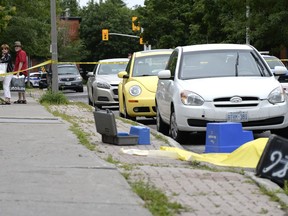 People look on at the scene of an overnight homicide in Lowertown in Ottawa on Sunday, July 10, 2016.