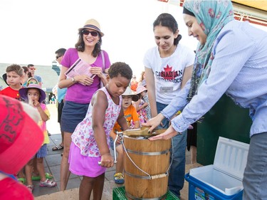 Susanna Leblond-Musu, 4, (L) helps make ice cream the old fashion way using a manual ice cream maker with volunteers Meriam Zeghal and Manel Zeghal (R) assisting as the National Ice Cream Day is celebrated at the Ice Cream Festival taking place Sunday at the Canada Agriculture and Food Museum.