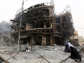 Iraqi women walk past a damaged building at the site of a suicide car bombing claimed by the Islamic State group on July 3, 2016 in Baghdad's central Karrada district. The blast, which ripped through a street in the Karrada area where many people go to shop ahead of the holiday marking the end of the Muslim fasting month of Ramadan, killed at least 75 people and also wounded more than 130 people, security and medical officials said. The Islamic State group issued a statement claiming the suicide car bombing, saying it was carried out by an Iraqi as part of the group's "ongoing security operations".