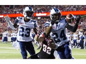 The Toronto Argonauts' T.T. Heath looks on as teammate A.J. Jefferson hauls in a loose ball in front of the Redblacks' Zack Evans.