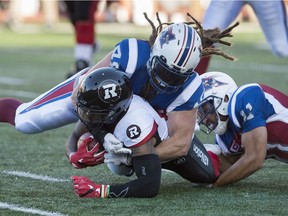 Ottawa Redblacks running back Travon Van is tackled by Montreal Alouettes linebacker Bear Woods and linebacker Chip Cox, right, during first quarter CFL football action, in Montreal on Thursday, June 30, 2016.