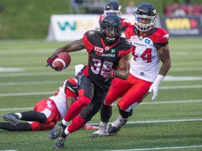 The Ottawa Redblacks' Tristan Jackson runs with the ball with the Calgary Stampeders' Ben D'Auilar in pursuit during the second quarter at TD Place stadium on Friday, July 8, 2016.
