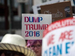 A young woman holds a sign against US Republican presidential candidate Donald Trump as people march in support of clean energy and the environment in Philadelphia on July 24, 2016, one day before the Democrats gather to formally annoint Hillary Clinton as their candidate for the November presidential election at the Democratic National Convention. /