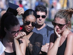 Women react near the scene where a truck mowed through revelers in Nice, southern France, Friday, July 15, 2016.  A Tunisian living in France drove a large truck through crowds celebrating Bastille Day along Nice's beachfront, killing more than 80 people, many of them children, according to police and hospital officials.