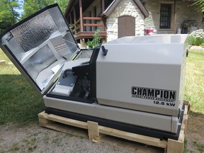 An automatic standby generator awaiting installation. The open half of the weatherproof enclosure shows part of the engine.