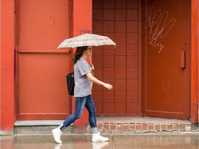 A woman seeks refuge under an umbrella.