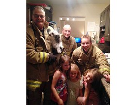 Members of Ottawa Fire Services pose with three young girls and their dog, Luna, shortly after freeing the dog from a sink drain.