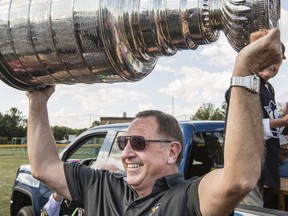 Jacques Martin, assistant coach with the Pittsburgh Penguins hoists the 2016 Stanley Cup trophy in a park in Clarence-Rockland, ON Monday, August 8, 2016.