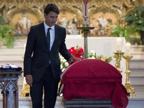 Prime Minister Justin Trudeau touches the casket of MP Mauril Belanger after delivering a eulogy during his funeral at the Notre-Dame Cathedral Basilica, on Saturday, Aug. 27, 2016 in Ottawa.