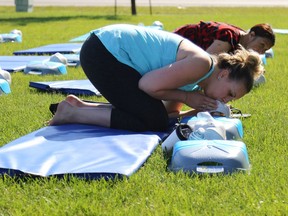 Lindsay Burt (left) and Francisca Wanchaken practise blowing air into a person's mouth using adult training mannequins at an outdoor CPR and automated external defibrillators (AED) information session during St. John Day at St. John Ambulance Grande Prairie Centre on 109 Street on Wednesday June 24, 2015 in Grande Prairie, Alta. The participants also learned some first aid skills to use when an adult, child or an infant is choking. In addition to the information session, St. John Ambulance staff and volunteers were also available to talk about the organization throughout the day.  Alexa Huffman/Grande Prairie Daily Herald-Tribune/Postmedia Network ORG XMIT: POS1607230515587509