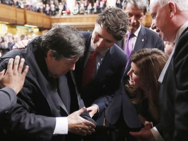 Liberal MP Mauril Belanger (left) shakes hands with Conservative Interim Leader Rona Ambrose as he is helped by Prime Minister Justin Trudeau (centre) after he sat in the Speaker's Chair to preside over the House of Commons in Ottawa Wednesday March 9, 2016.
