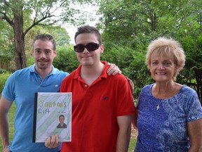 Jordan Cox (middle) poses with his book, Jordan's Gift in the backyard of his Nepean home.