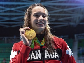 Canada's Penny Oleksiak holds up her gold medal after her first-place finish in the women's 100m freestyle finals during the 2016 Olympic Summer Games in Rio de Janeiro, Brazil, on Friday, Aug. 12, 2016.