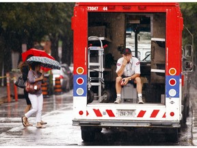 A Canada Post worker takes a break and shelter from an afternoon downpour inside his mail delivery truck at the corner of Gloucester and Elgin Sts. in Ottawa Thursday July 14, 2016.