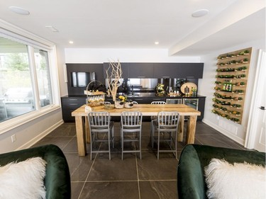 Wet bar: A repeat of the pantry cabinetry, the matte black finish in the wet bar is paired with a high-gloss one for an edgy rustic feel. A hanging wine rack made from the same rough-sawn oak veneer as the home theatre wall was inspired by the modern industrial look and black accents sought throughout the home.