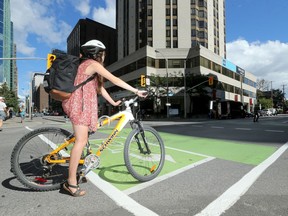 A woman on her bike, at the corner of Lyon and Laurier, across from the scene of a fatal collision that occurred Thursday (Sept. 1, 2016).  Flowers were already gathering around a hydrant (far right) Thursday afternoon in honour of the young female cyclist who died after colliding with a dump truck.   Julie Oliver/Postmedia