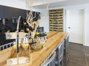 Wet bar: A repeat of the pantry cabinetry, the matte black finish in the wet bar is paired with a high-gloss one for an edgy rustic feel. A hanging wine rack made from the same rough-sawn oak veneer as the home theatre wall was inspired by the modern industrial look and black accents sought throughout the home.