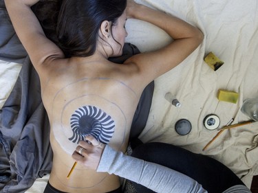 Artist May Mutter in the early stages of creating a full-body painting on Marie-Claude Messier. Both women have suffered serious concussions. (Bruce Deachman, Ottawa Citizen)