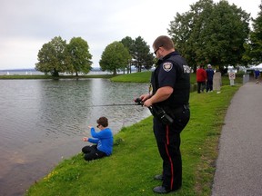Carson McKay, 10, uses his hands to reel in his line as he learned fishing under the watchful eye of Const. Adam Elliott on Saturday, Sept. 17.