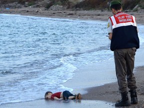 This photo, taken on Sept. 2, 2015, shows a Turkish police officer standing next to the body of Alan Kurdi, which had washed up on the shore in Bodrum, southern Turkey, after a boat carrying refugees sank while trying to reach the Greek island of Kos. The starkness of the photo galvanized Canadians into action.