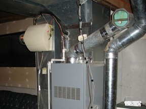 It's not unusual for furnace humidifiers to make homes too moist in winter. The beige, cylindrical object towards the left of the furnace is the humidifier with its controls.
Photo credit: Canstock Photo
