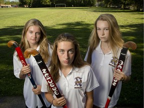 Claire Adams, Jayden Alp, and Tay Barnabe, members of the championship-defending Nepean High School varsity field hockey team, pose for a photo at their school's field.