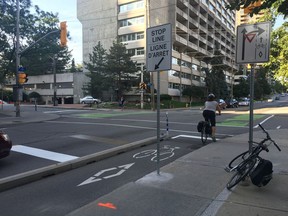 A cyclist stops at Laurier Avenue and Bay Street where the stop lines for vehicles have been moved back and for cyclists ahead, increasing the distance between the two to five metres.