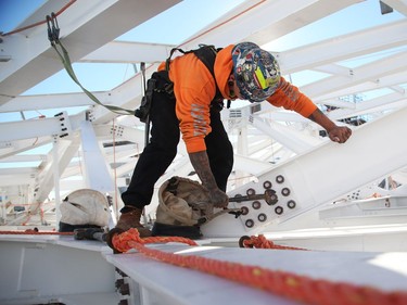 A steel worker works on the new roof of the West Block.