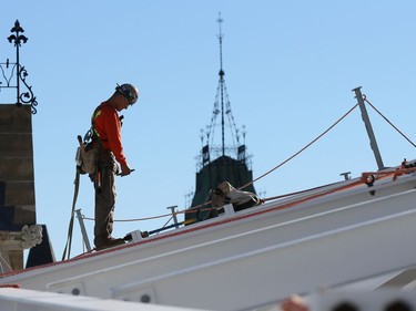 A steel worker works on the new roof of the West Block.